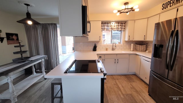 kitchen featuring light wood finished floors, white dishwasher, a sink, light countertops, and stainless steel fridge