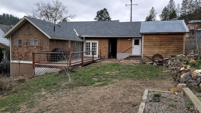 back of house with a yard, roof with shingles, a wooden deck, and a chimney