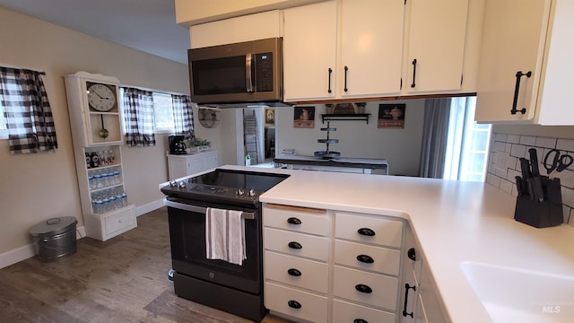 kitchen featuring dark wood-type flooring, white cabinets, light countertops, black range with electric stovetop, and stainless steel microwave