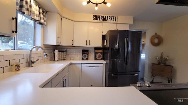 kitchen featuring white cabinetry, a sink, dishwasher, tasteful backsplash, and black refrigerator with ice dispenser