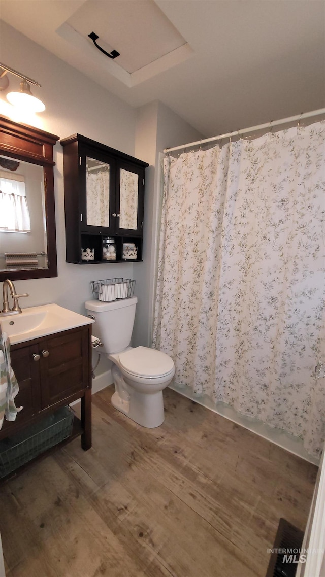 bathroom with toilet, vanity, a shower with curtain, and wood finished floors