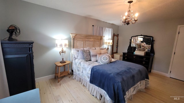 bedroom featuring baseboards, a chandelier, and light wood finished floors