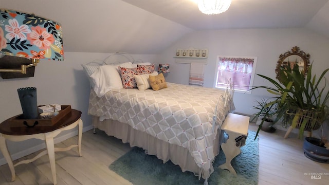 bedroom with light wood-type flooring and lofted ceiling