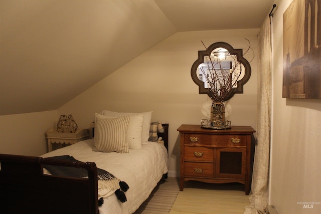 bedroom featuring light wood-type flooring and vaulted ceiling