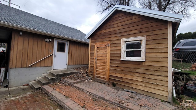 entrance to property with fence and a shingled roof