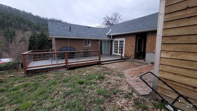 back of property featuring french doors, a shingled roof, and a deck