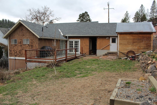 back of property with a shingled roof, a chimney, french doors, a deck, and a lawn