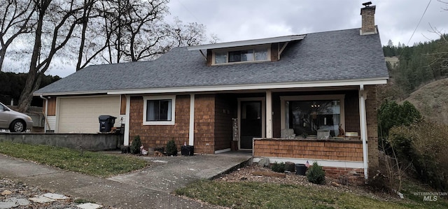 view of front of home with a garage, covered porch, a chimney, and roof with shingles