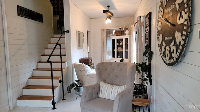 living area featuring wooden walls and stairs