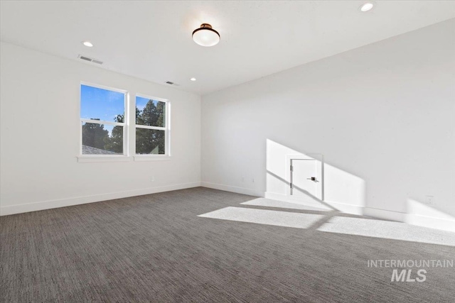 unfurnished room with dark colored carpet