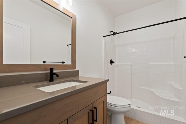 bathroom featuring a shower, vanity, hardwood / wood-style flooring, and toilet