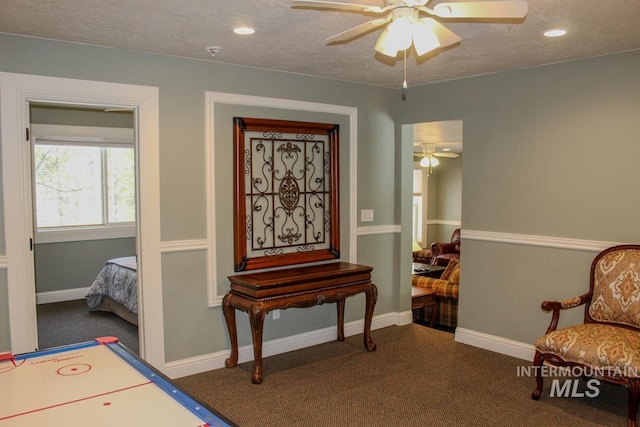 sitting room with ceiling fan, a textured ceiling, and dark carpet