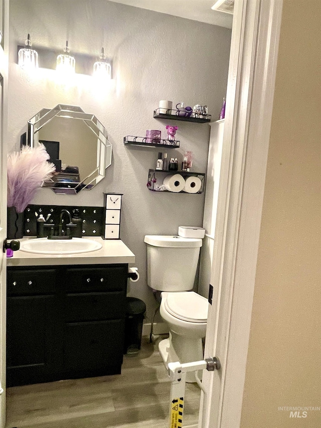 bathroom with hardwood / wood-style flooring, vanity, and toilet