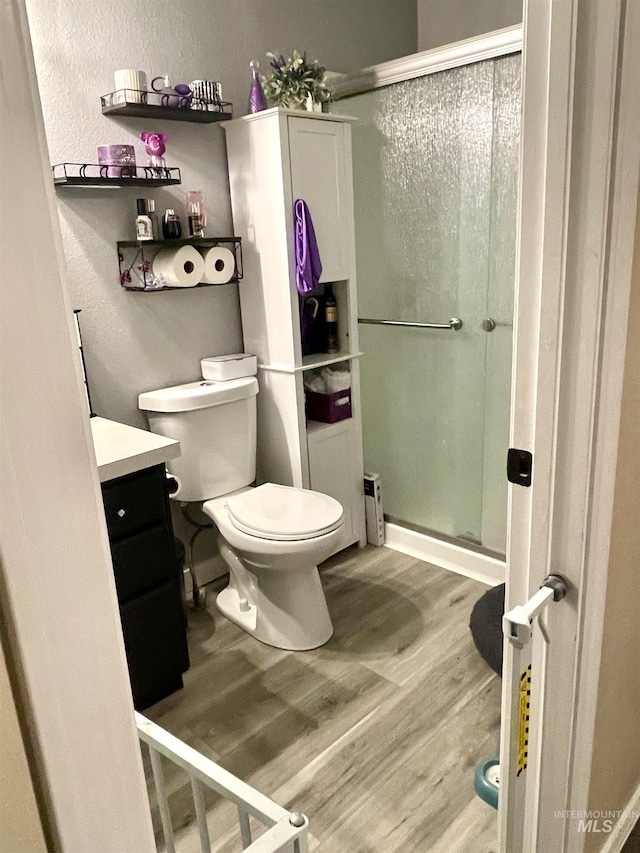 bathroom with hardwood / wood-style flooring, vanity, toilet, and a shower with door