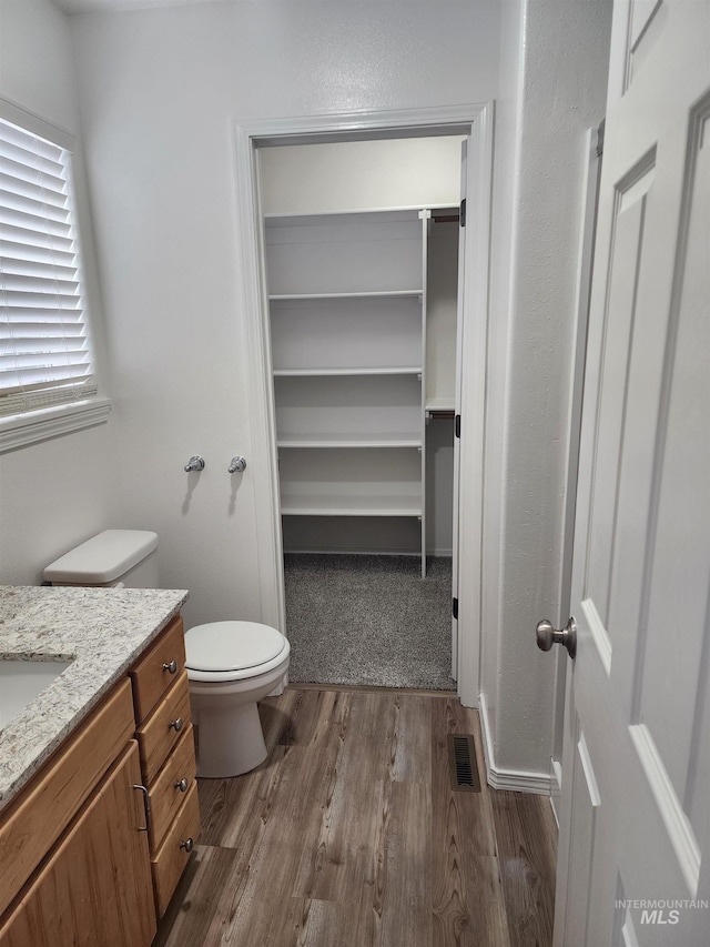 bathroom with hardwood / wood-style floors, toilet, and vanity