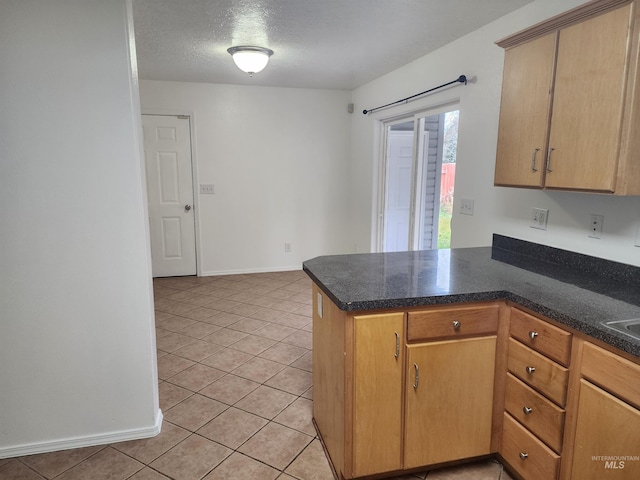 kitchen with kitchen peninsula, light tile patterned flooring, and a textured ceiling