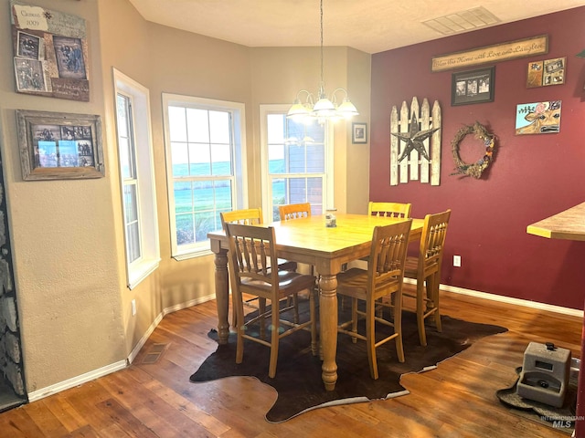 dining area with an inviting chandelier and dark wood-type flooring