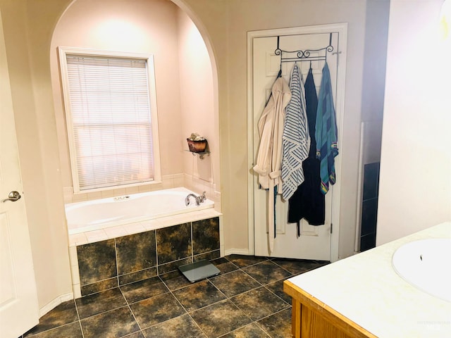 bathroom with tiled tub and vanity