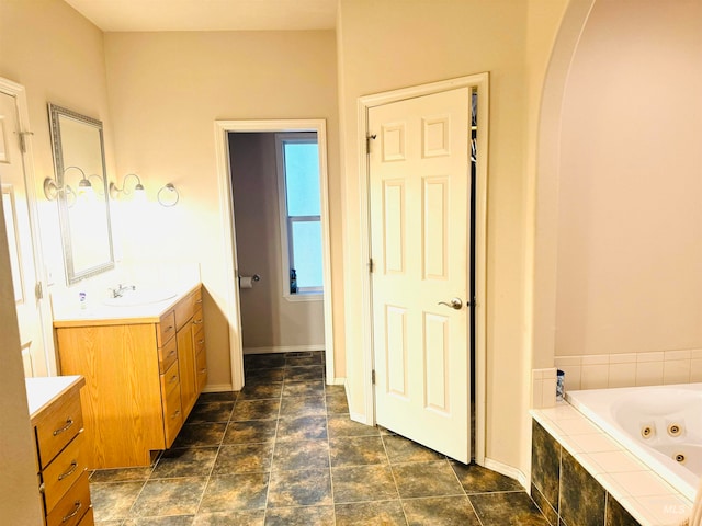 bathroom with tiled tub and vanity