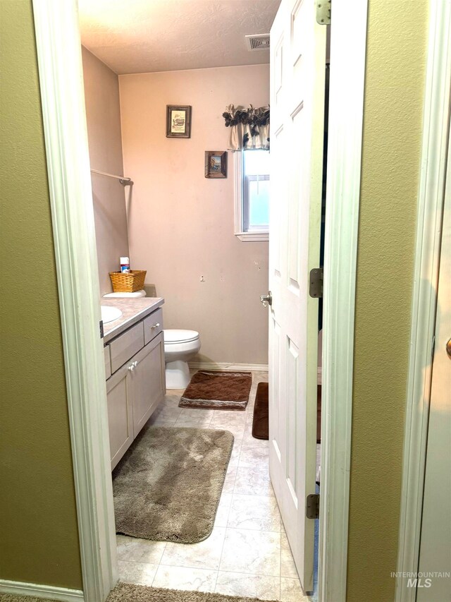 bathroom with a textured ceiling, vanity, and toilet