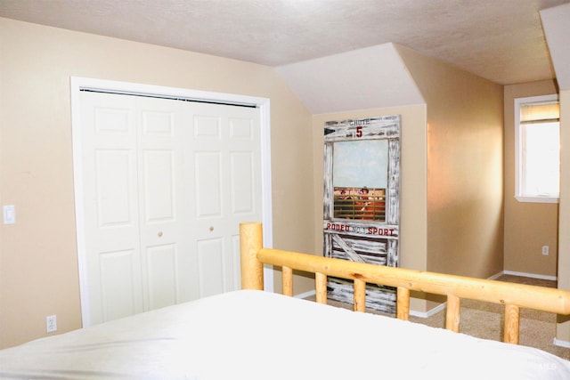 bedroom with a textured ceiling, a closet, and lofted ceiling