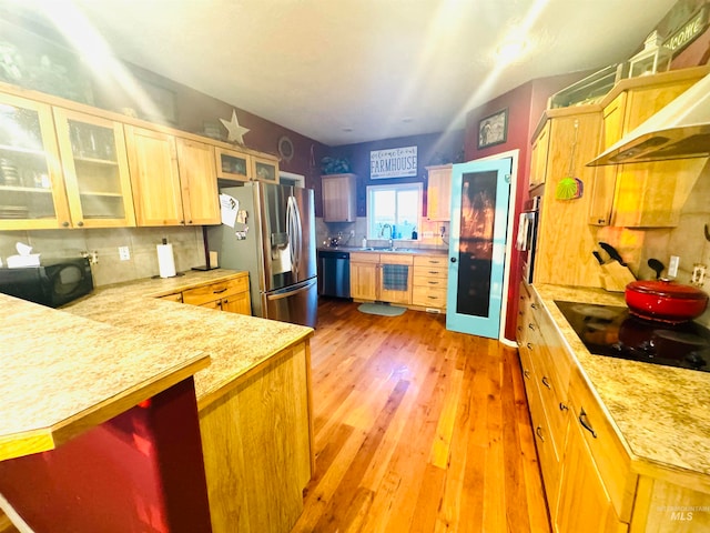 kitchen featuring light hardwood / wood-style floors, backsplash, wall chimney exhaust hood, light brown cabinets, and black appliances