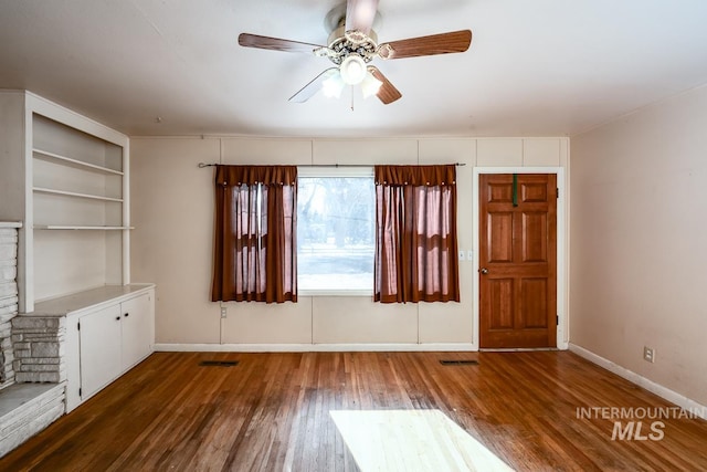 interior space featuring dark wood-type flooring, ceiling fan, and built in shelves