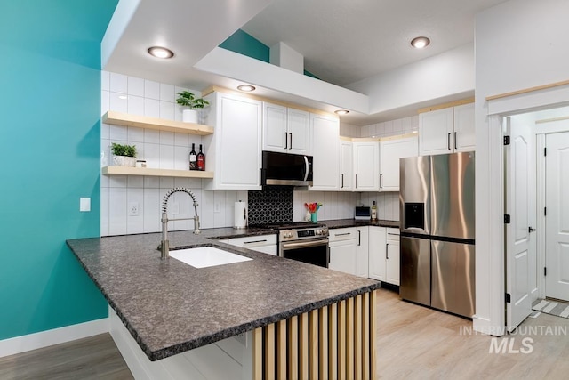 8079 W Beckton Ln, Garden City, ID 83714 - kitchen with appliances with stainless steel finishes, a sink, a peninsula, light wood-type flooring, and backsplash