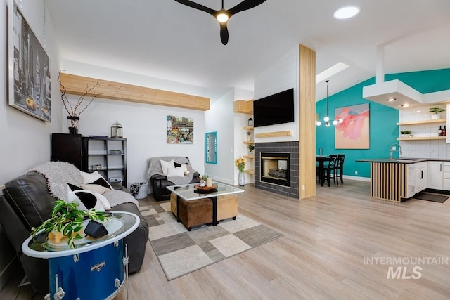 8079 W Beckton Ln, Garden City, ID 83714 - living room with a ceiling fan, light wood-style flooring, lofted ceiling, a tile fireplace, and baseboards
