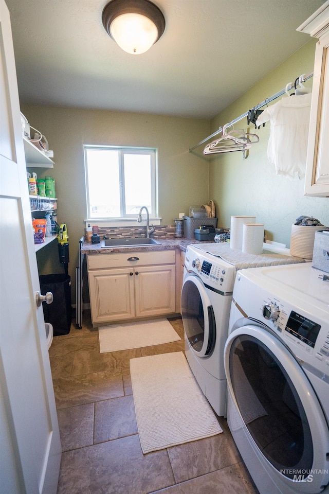 laundry area with cabinet space, stone finish floor, washer and clothes dryer, and a sink