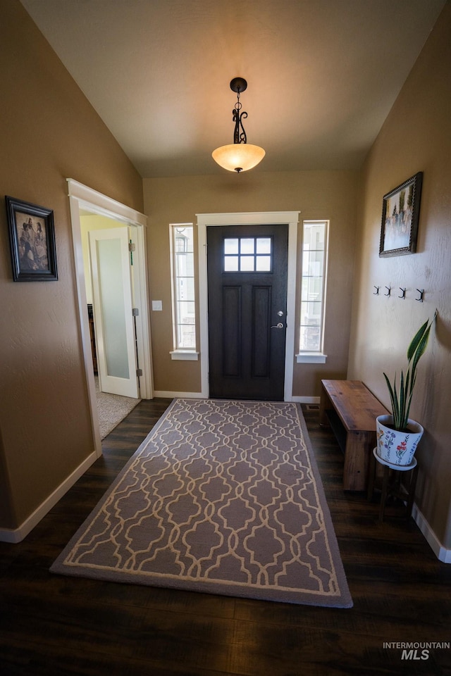 foyer with dark wood-type flooring, vaulted ceiling, and baseboards
