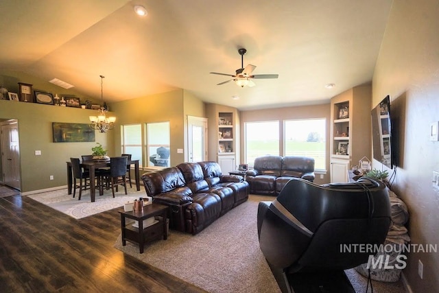 living area featuring vaulted ceiling, wood finished floors, ceiling fan with notable chandelier, built in features, and baseboards