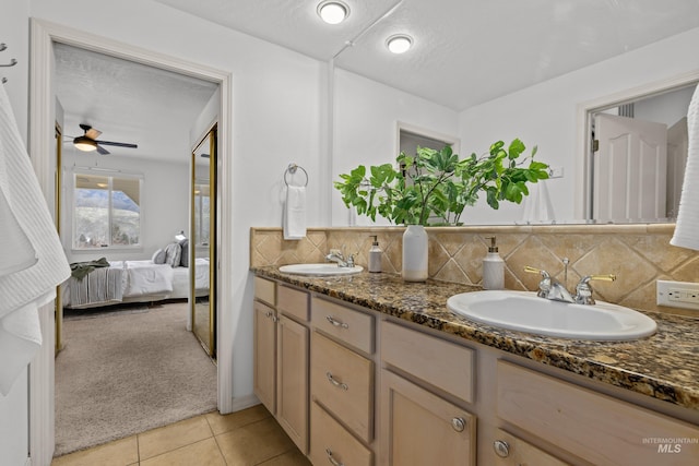 ensuite bathroom with tasteful backsplash, a sink, ensuite bath, and tile patterned floors