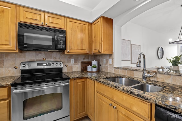 kitchen with tasteful backsplash, arched walkways, dark stone counters, black appliances, and a sink