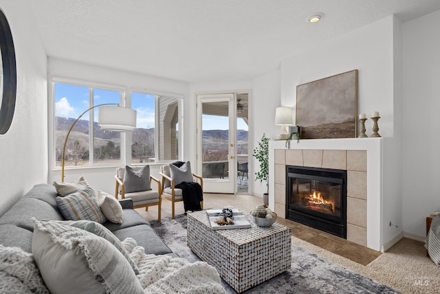 carpeted living area with a tile fireplace, a mountain view, and baseboards