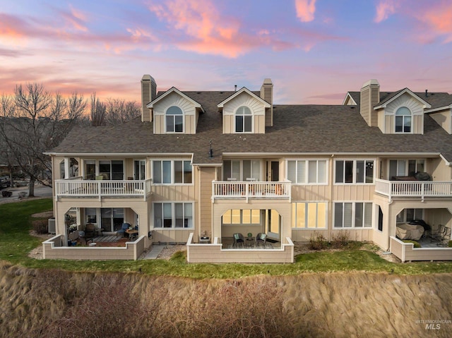 back of house featuring a balcony, a patio area, and board and batten siding