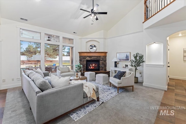 living area with visible vents, high vaulted ceiling, a stone fireplace, baseboards, and ceiling fan