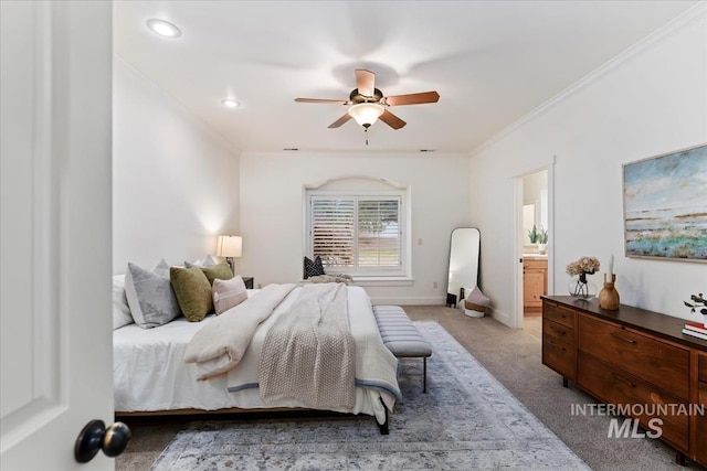 carpeted bedroom featuring baseboards, a ceiling fan, ensuite bath, and crown molding