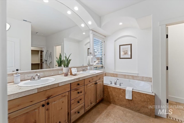 full bathroom featuring a garden tub, double vanity, visible vents, and a sink