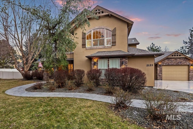 view of front of house with fence, stucco siding, a front lawn, concrete driveway, and stone siding