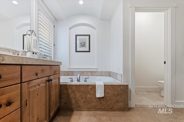 bathroom featuring vanity, a garden tub, and toilet