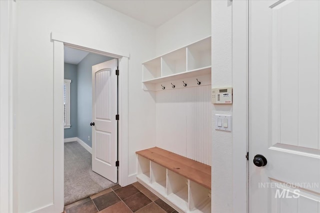 mudroom featuring dark tile patterned flooring, baseboards, and dark carpet