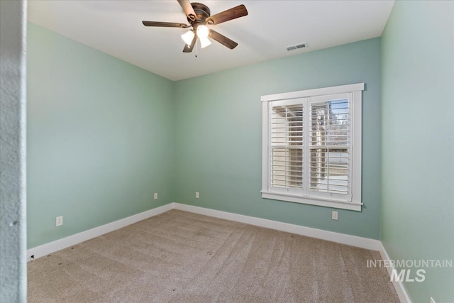 carpeted empty room with visible vents, baseboards, and a ceiling fan