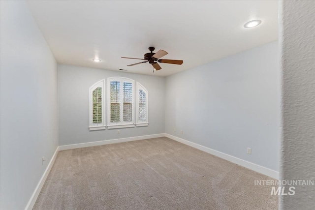 carpeted spare room with baseboards and a ceiling fan