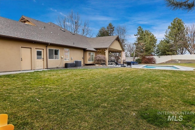 rear view of property with central air condition unit, a yard, stucco siding, and fence