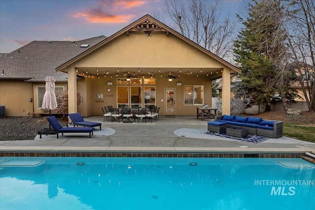 pool at dusk featuring a patio area, an outdoor pool, and an outdoor hangout area