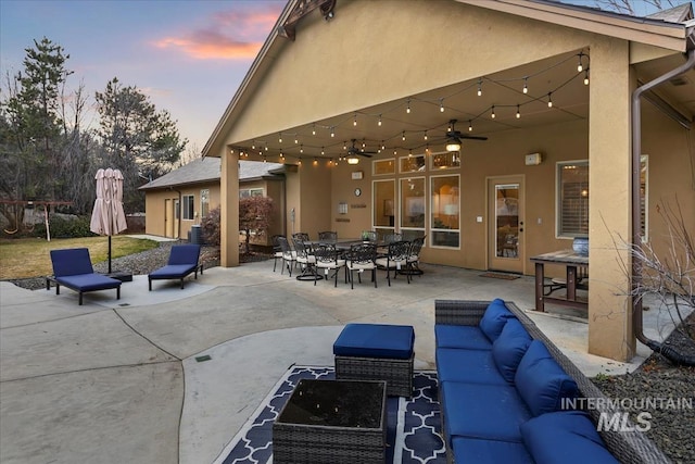 patio terrace at dusk with outdoor dining space, outdoor lounge area, and a ceiling fan