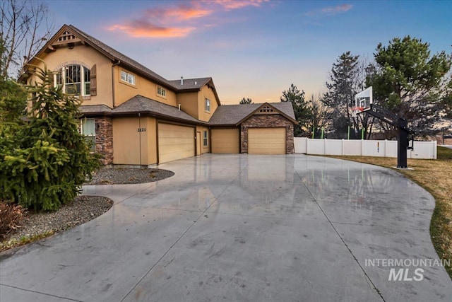 view of front of house featuring fence, stone siding, and stucco siding