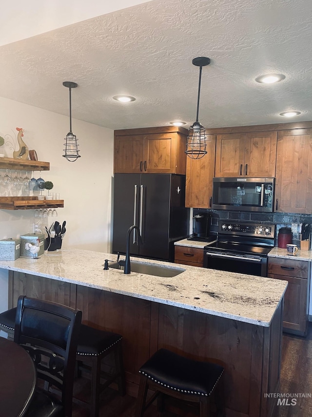 kitchen featuring pendant lighting, kitchen peninsula, sink, and black appliances