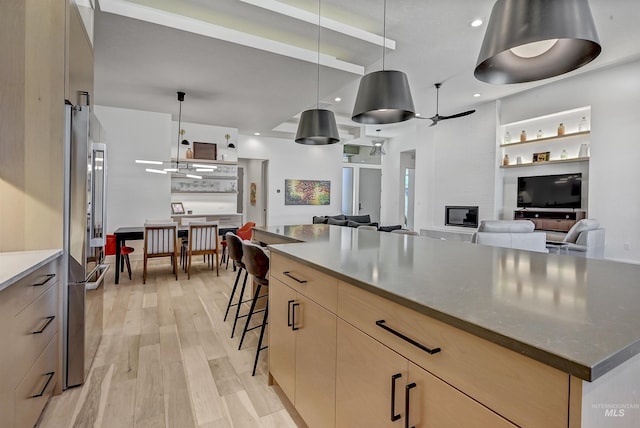 2313 S Aburge Ave, Meridian, ID 83642 - kitchen featuring light brown cabinetry, light wood-style floors, high quality fridge, modern cabinets, and a kitchen bar